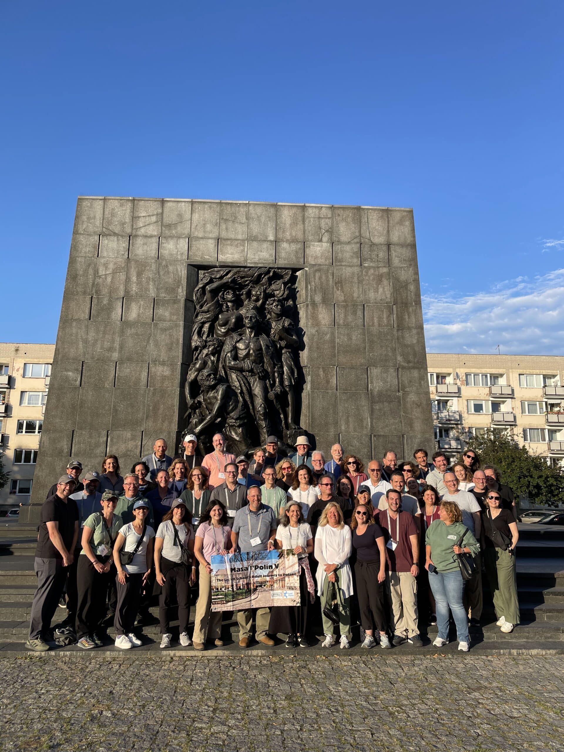 Masa l'Polin Adult trip to Poland 2025. Group photo in front of the Rapaport Monument in Warsaw, Poland